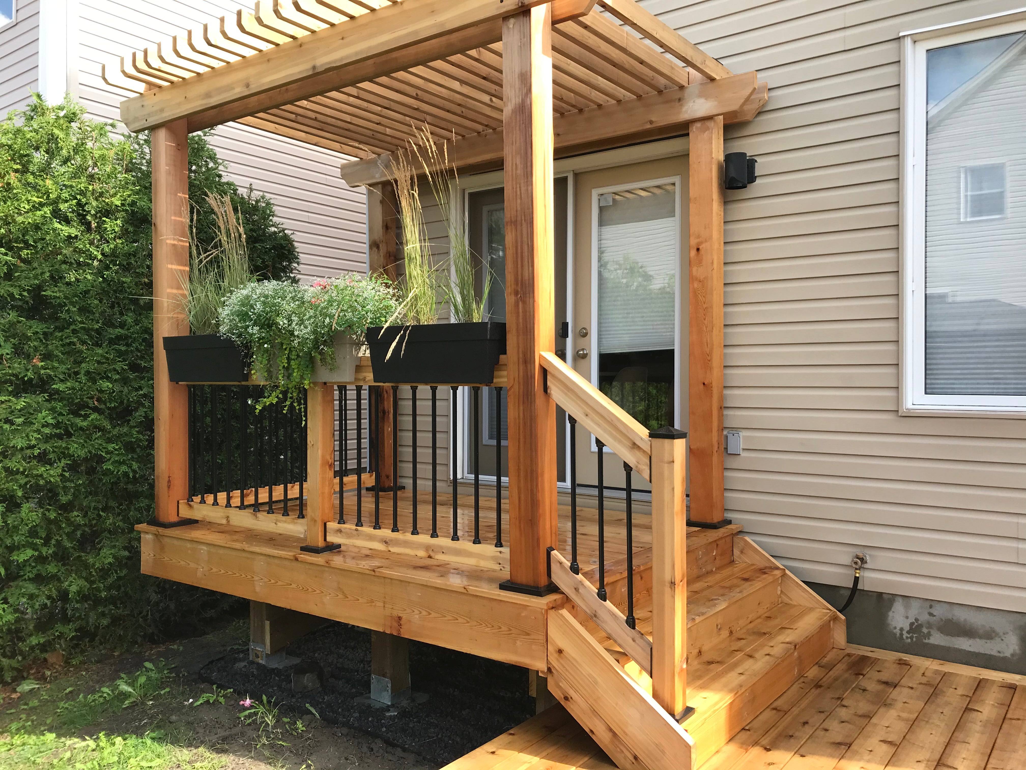 Wooden deck with pergola and planters against a house exterior