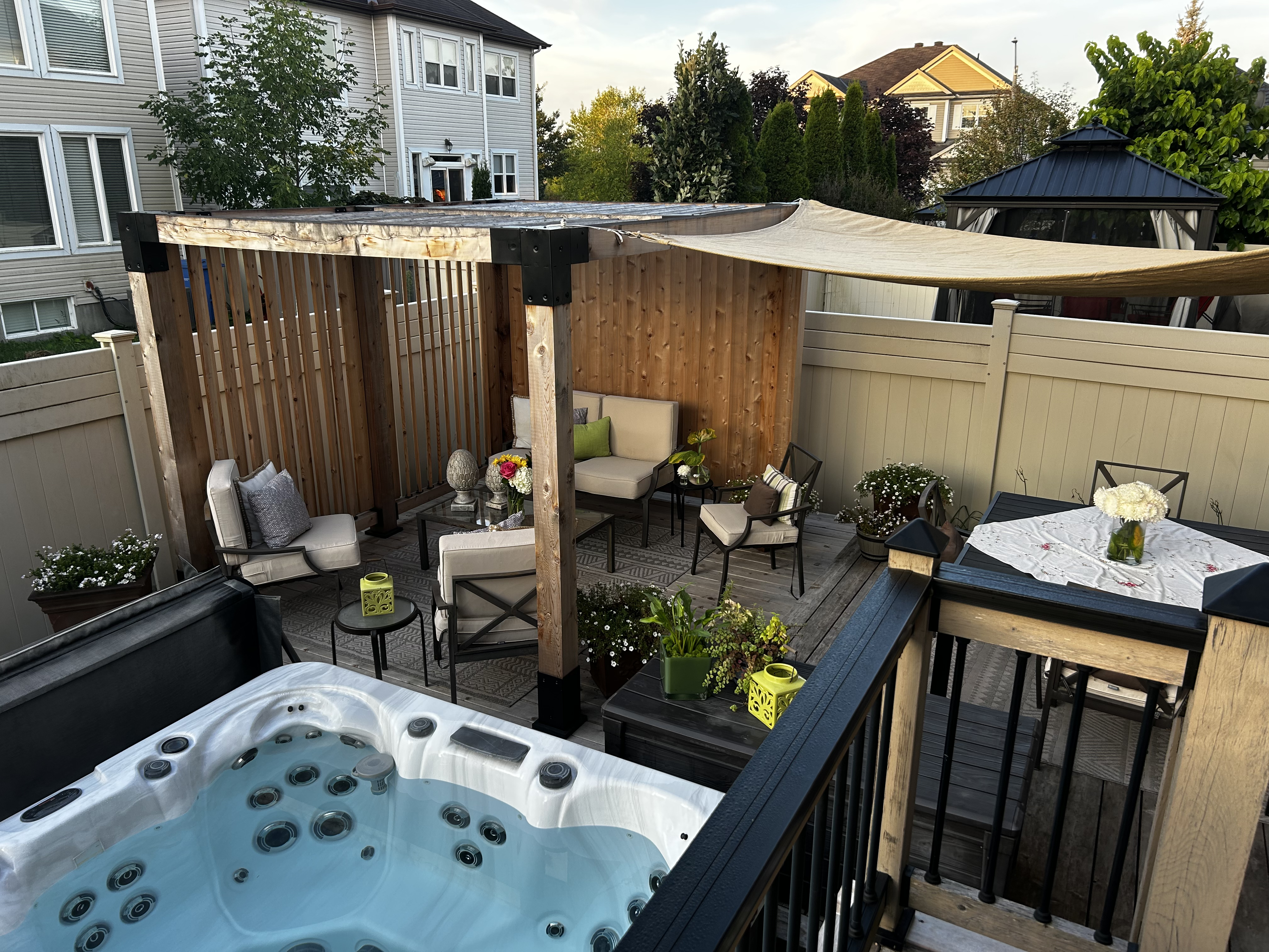 Outdoor patio with hot tub, seating area, and pergola on a residential property.